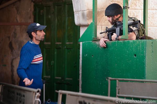A Palestinian man is questioned at an Israeli military checkpoint. 