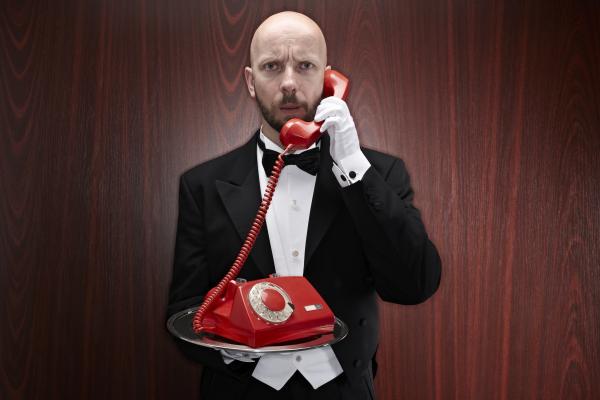 Butler with a red telepfone on a silver tray. Photo via Getty Images. 