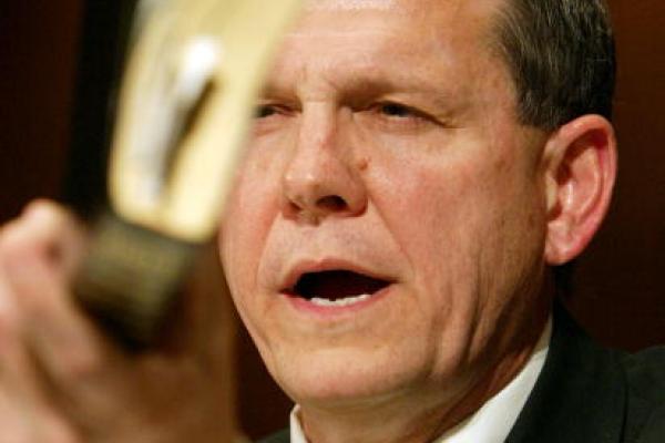 Justice Roy Moore holds a Bible while testifying in a hearing. Via Getty Images.