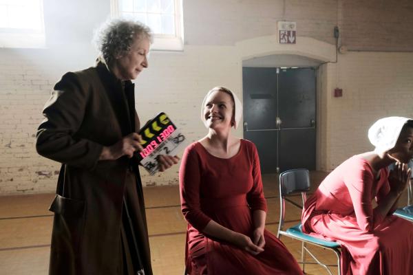 Margaret Atwood holds a slate while laughing with Elizabeth Moss during filming of The Handmaid's Tale series. 