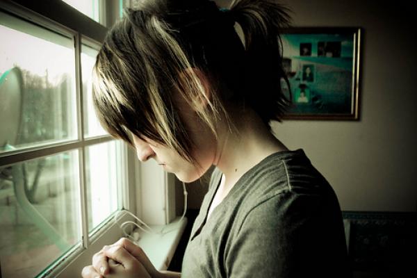 A young woman in prayer. Image via Wylio.