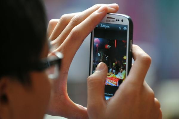 Man using Instagram to share photo, 1000 Words / Shutterstock.com