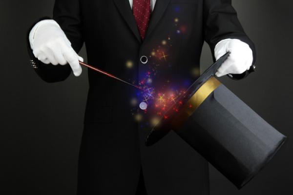 Magician performing on dark background, Africa Studio / Shutterstock.com