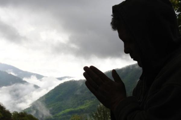 A figure prays while a storm rolls in. Image courtesy Waddell Images/shutterstoc