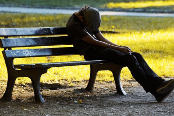 An impoverished young man man on a bench. Photo courtesy Dariush M/shutterstock.