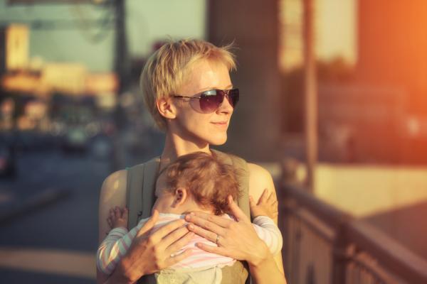 A mother carries her child through a city. Image via Konstantin Sutyagin/shutter