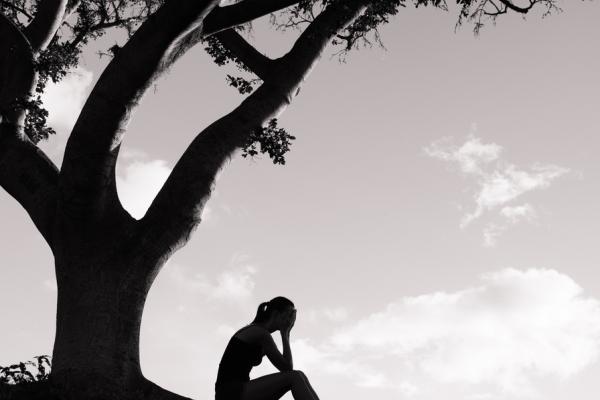 A figure weeps under a tree. Image courtesy KieferPix/shutterstock.com