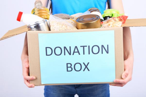 A young man holds a box of donations. Image courtesy Africa Studio/shutterstock.