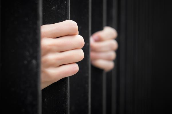 Hands on prison bars. Image courtesy Kaspars Grinvalds/shutterstock.com