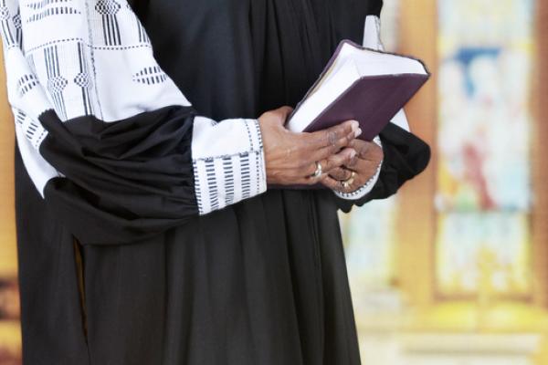 Female clergy holding a Bible, glenda / Shutterstock.com