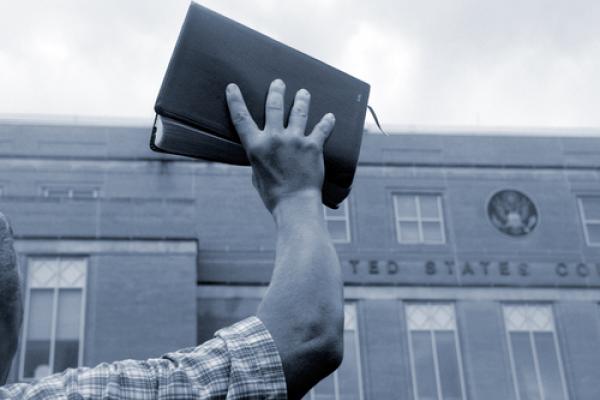 Man holding up Bible in front of court house, Cheryl Casey / Shutterstock.com