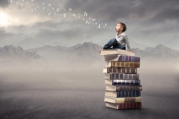 Photo: Child sitting on stack of books, olly / Shutterstock.com