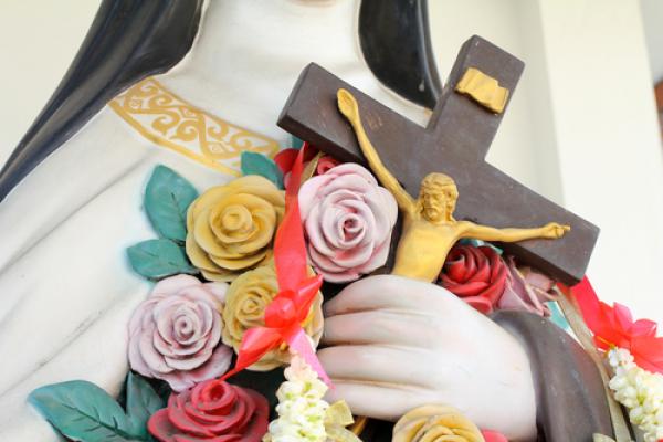 Flowers and crucifix in the hand of holy women. Image via GOLFX/shutterstock.com