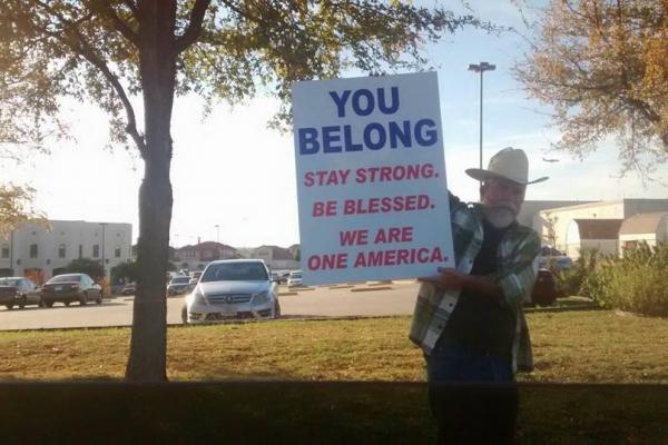 A man in a cowboy hat holds a sign of support outside of a mosque in Irving, Tx