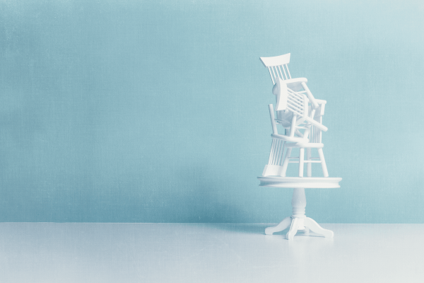 Illustration of white chairs piled haphazardly on top of a dining table