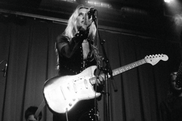 Black and white photo of Natalie Bergman holding an electric guitar and singing into a mic stand
