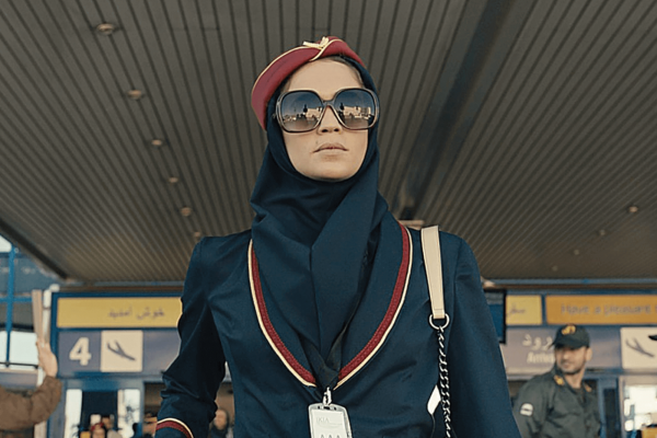 A spy dressed as a flight attendant with sunglasses exits the Tehran airport