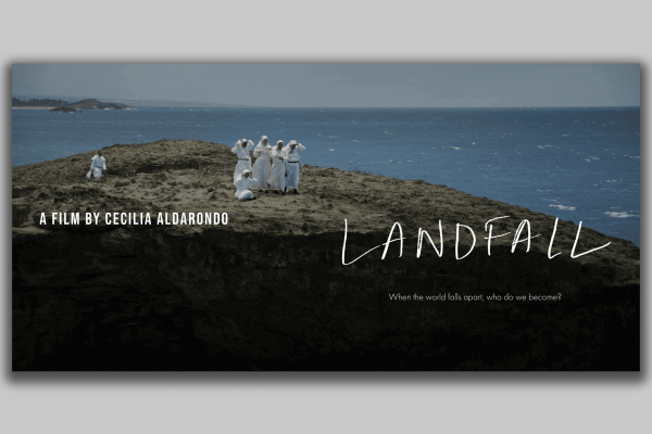 A group of people wearing white stand on the edge of the land where it meets the sea