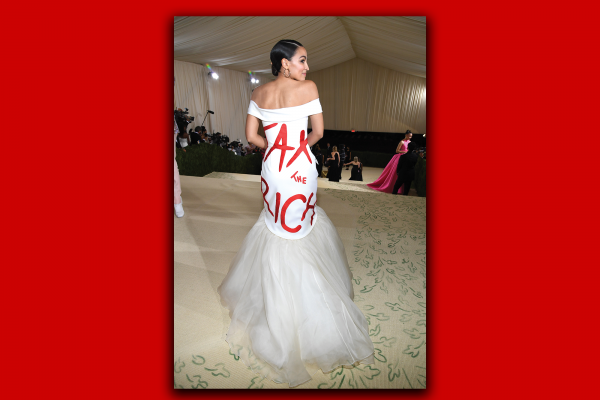 Alexandria Ocasio-Cortez stands with her back to the camera, displaying a ball gown that says "Tax the Rich."