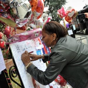 Fan signs a poster for singer Whitney Houston at the New Hope Baptist Church, Ne