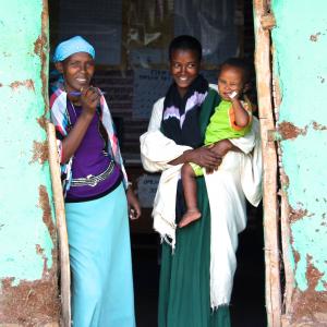 A mother and her 18-month-old child stand with a health care worker at a clinic in rural Ethiopia. Photo by Cathleen Falsani.