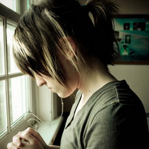 A young woman in prayer. Image via Wylio.