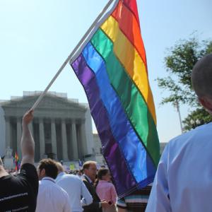 A man holds a gay pride flag in front of the Supreme Court. Photo via Adelle M. Banks / RNS Photo via Adelle M. Banks / RNS