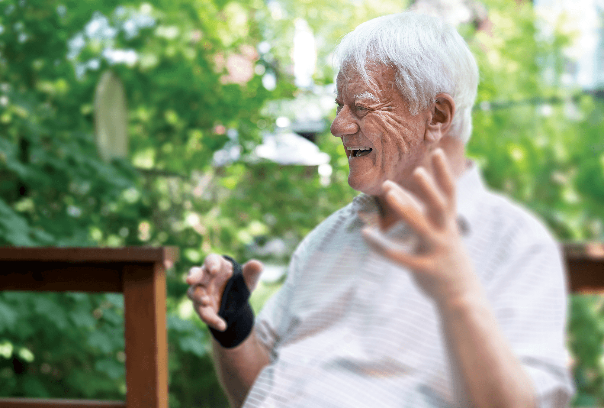 Profile of Lakey seated, laughing. A wrist brace is visible