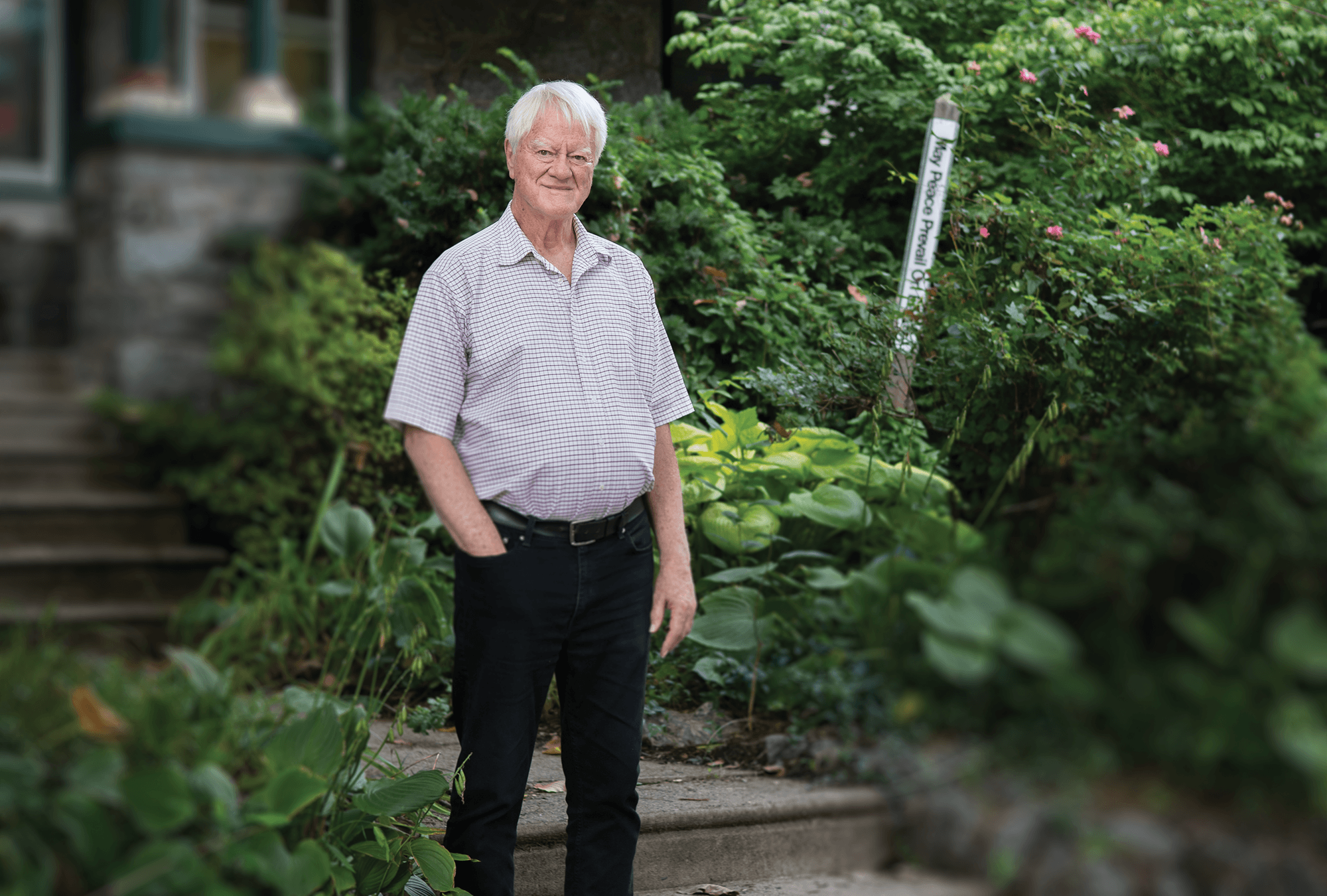 Lakey standing at his porch steps, surrounded by foliage