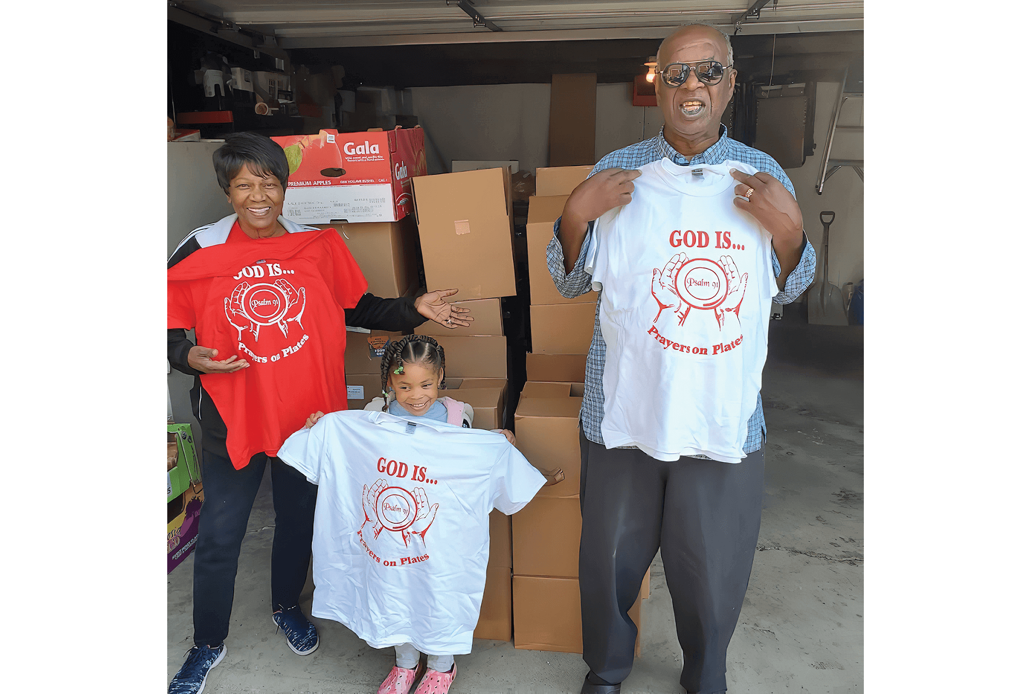 Photo Credit: Antonio Hill A Black family holds up t-shirts that say "God is prayers on plates."
