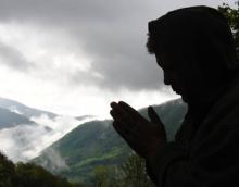 A figure prays while a storm rolls in. Image courtesy Waddell Images/shutterstoc