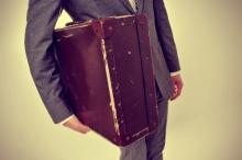 A young man carries an old suitcase. Image courtesy nito/shutterstock.com.