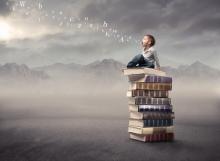 Photo: Child sitting on stack of books, olly / Shutterstock.com