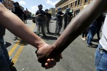 Community members hold hands in front of police officers in Baltimore on April 28, 2015. Photo via REUTERS / Jim Bourg / RNS Photo via REUTERS / Jim Bourg / RNS
