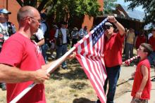 Taylor Hewlett, 9, watches Josh Flowers and Nathan Rascher put away a flag across from the church. RNS photo by Kellie Kotraba RNS photo by Kellie Kotraba