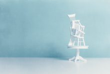 Credit: Catherine MacBride / Getty Images Illustration of white chairs piled haphazardly on top of a dining table