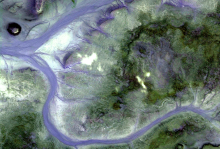 An aerial view of two rivers flowing around a green area of land