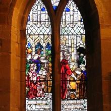 Stained glass church window depicting the Parable of the Talents from Matthew 25