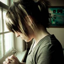 A young woman in prayer. Image via Wylio.