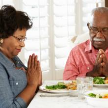 Couple praying at mealtime, Monkey Business Images / Shutterstock.com