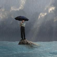 Man with an umbrella in a flood, photobank.kiev.ua / Shutterstock.com