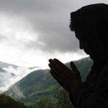 A figure prays while a storm rolls in. Image courtesy Waddell Images/shutterstoc