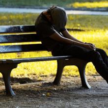 An impoverished young man man on a bench. Photo courtesy Dariush M/shutterstock.