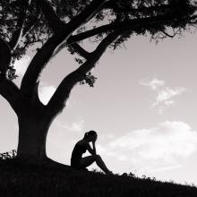 A figure weeps under a tree. Image courtesy KieferPix/shutterstock.com