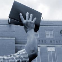 Man holding up Bible in front of court house, Cheryl Casey / Shutterstock.com