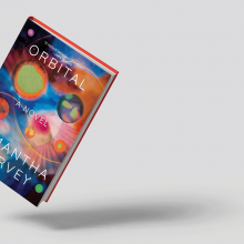 The image shows the cover of the book "orbital" which has rainbow colored planet shaped orbs 