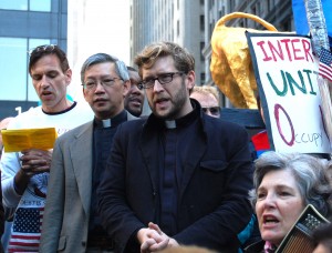 The Rev. Michael Ellick (center in black) leads a multi-faith service in Zuccotti Park on Sunday. Photo by Cathleen Falsani/Sojourners