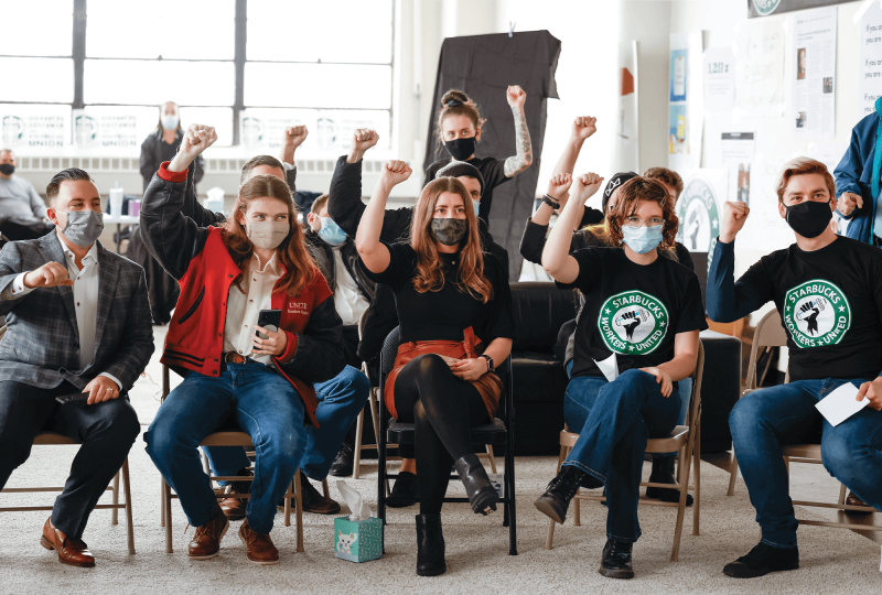 Starbucks employees hold raised fists in the air during a union vote