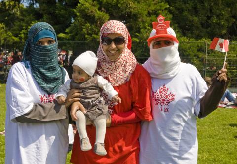 Muslim women stand waving a Canadian flag in anticipation of Canada Day festivities. Photo by George Rose/Getty Images Photo by George Rose/Getty Images