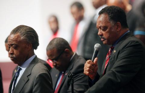 Rev. Al Sharpton bows his head as Rev. Jesse Jackson leads a prayer at a community forum. Photo Mario Tama/Getty Images Photo by Mario Tama/Getty Image